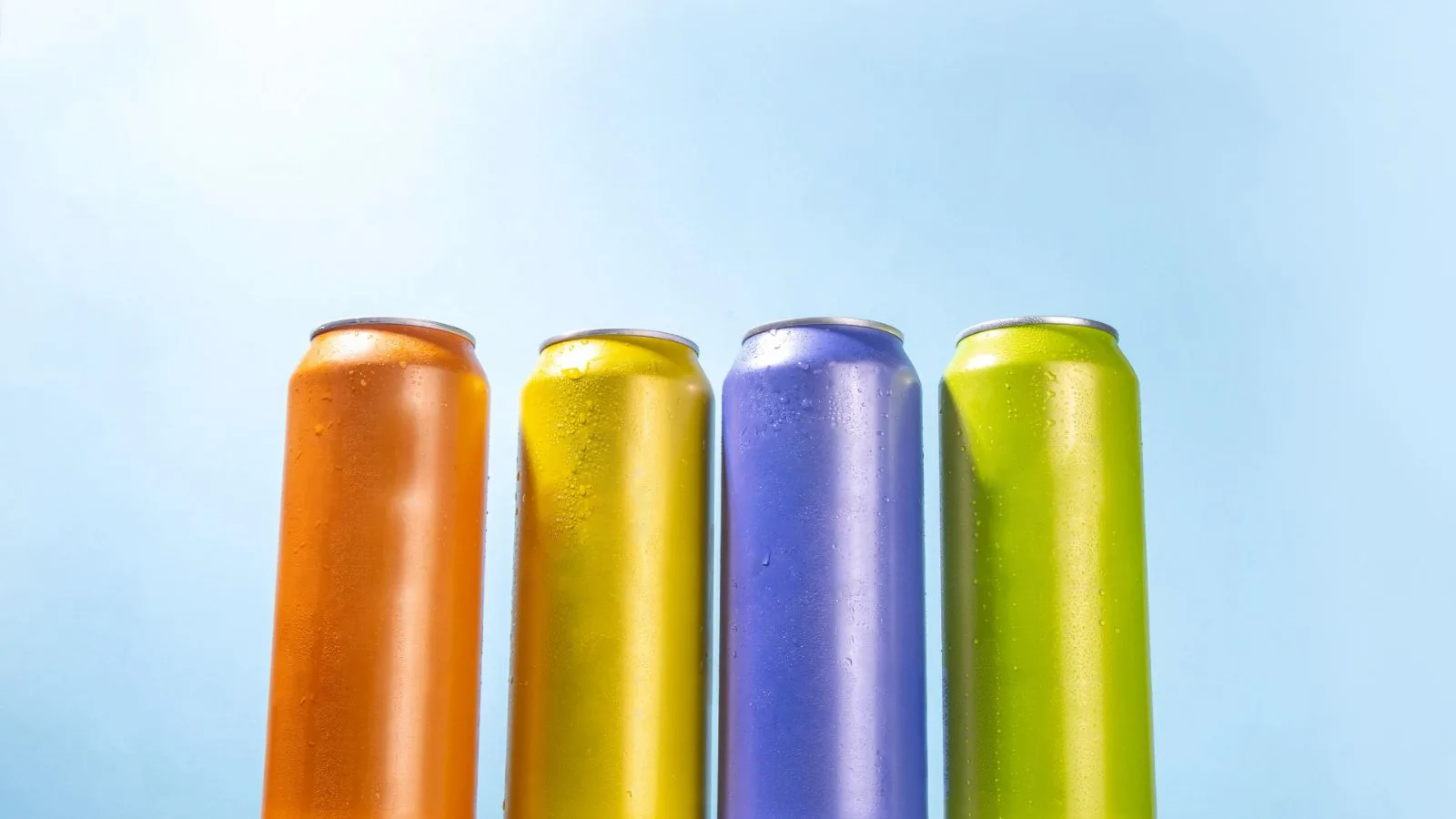 Four unlabelled soft-drink cans, chilled with condensation